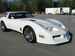 White Chevrolet Corvette C4 parked in an open lot with chrome wheels and Goodyear tires HD wallpaper