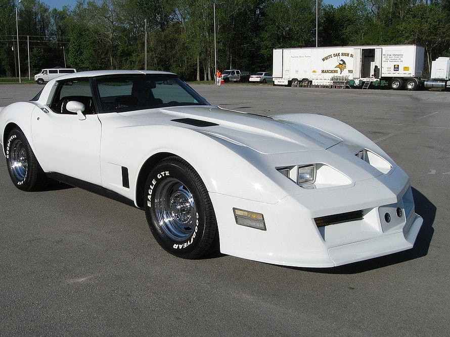 White Chevrolet Corvette C4 parked in an open lot with chrome wheels and Goodyear tires HD wallpaper