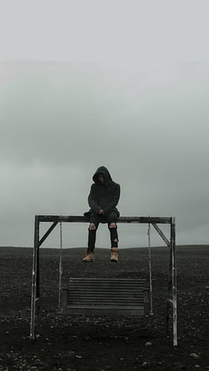 NF Sitting on a Swing Frame in a Desolate Landscape Under an Overcast Sky HD phone wallpaper
