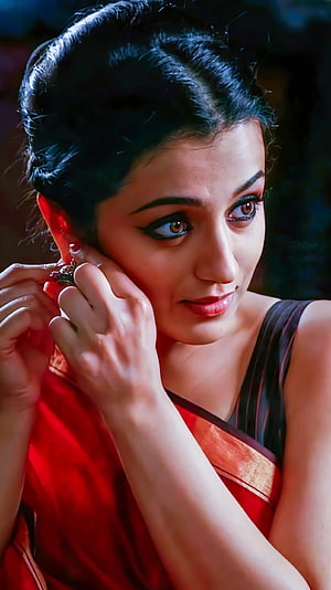 Trisha Krishnan in a red saree with gold border, adjusting an earring in a close-up portrait HD phone wallpaper