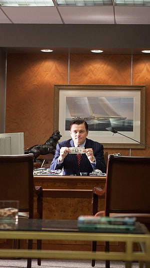 Leonardo DiCaprio in The Wolf of Wall Street holding a dollar bill in a luxury office HD phone wallpaper