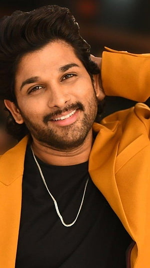 Allu Arjun in a mustard blazer and black tee, smiling with a silver chain necklace HD phone wallpaper
