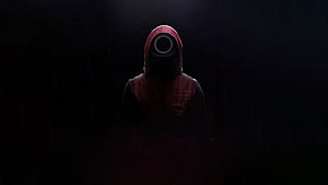 Squid Game Front Man Character in Red Hood and Mask Against Dark Background HD wallpaper