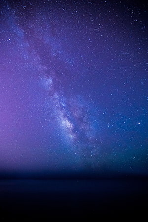 Milky Way Galaxy Arching Over a Dark Horizon in Deep Purple and Blue Tones HD phone wallpaper