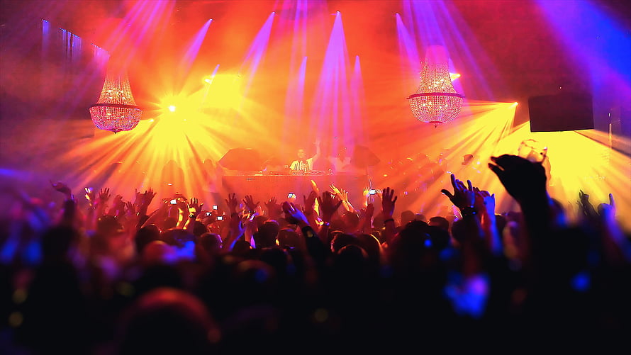 Vibrant nightclub crowd with raised hands under dramatic red and purple stage lighting HD wallpaper