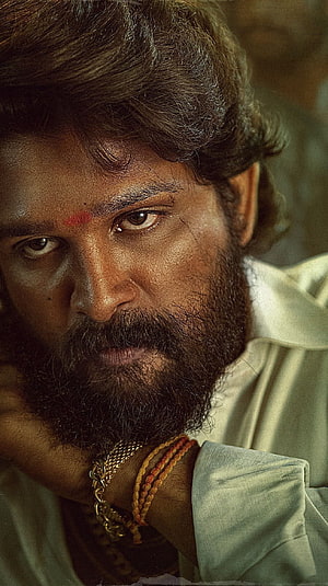 Allu Arjun as Pushpa in dramatic close-up with intense gaze and traditional markings HD phone wallpaper
