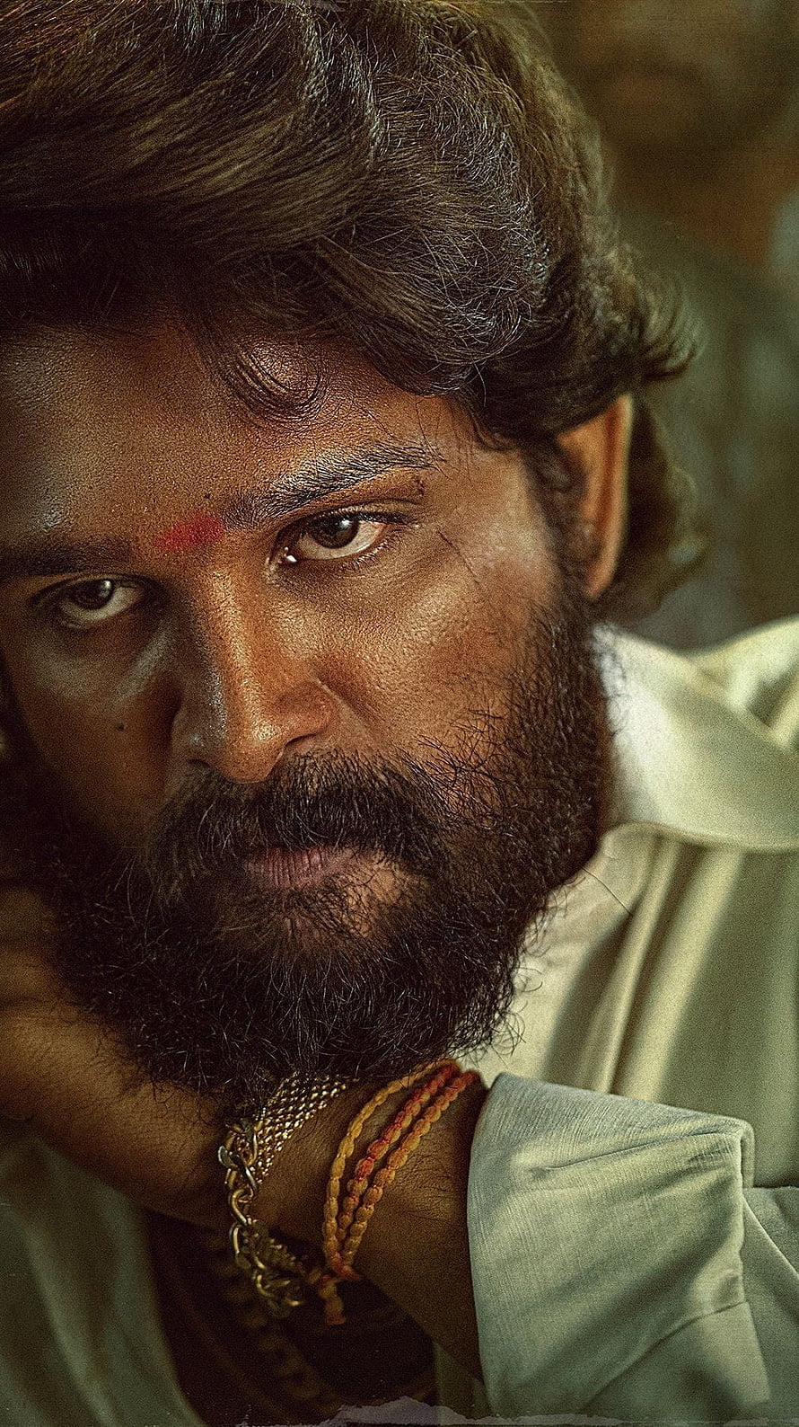 Allu Arjun as Pushpa in dramatic close-up with intense gaze and traditional markings HD phone wallpaper