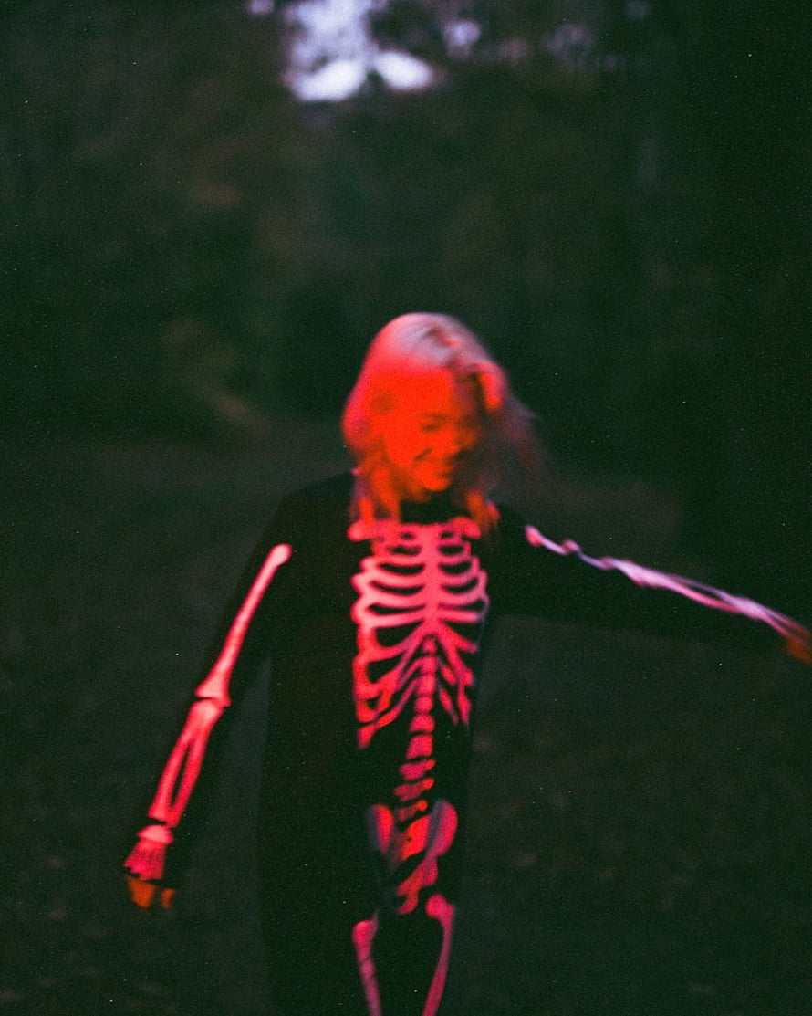 Phoebe Bridgers in a glowing skeleton bodysuit under red light in a dark forest HD phone wallpaper