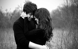 Black and White Portrait of a Young Couple Embracing in a Natural Field HD wallpaper