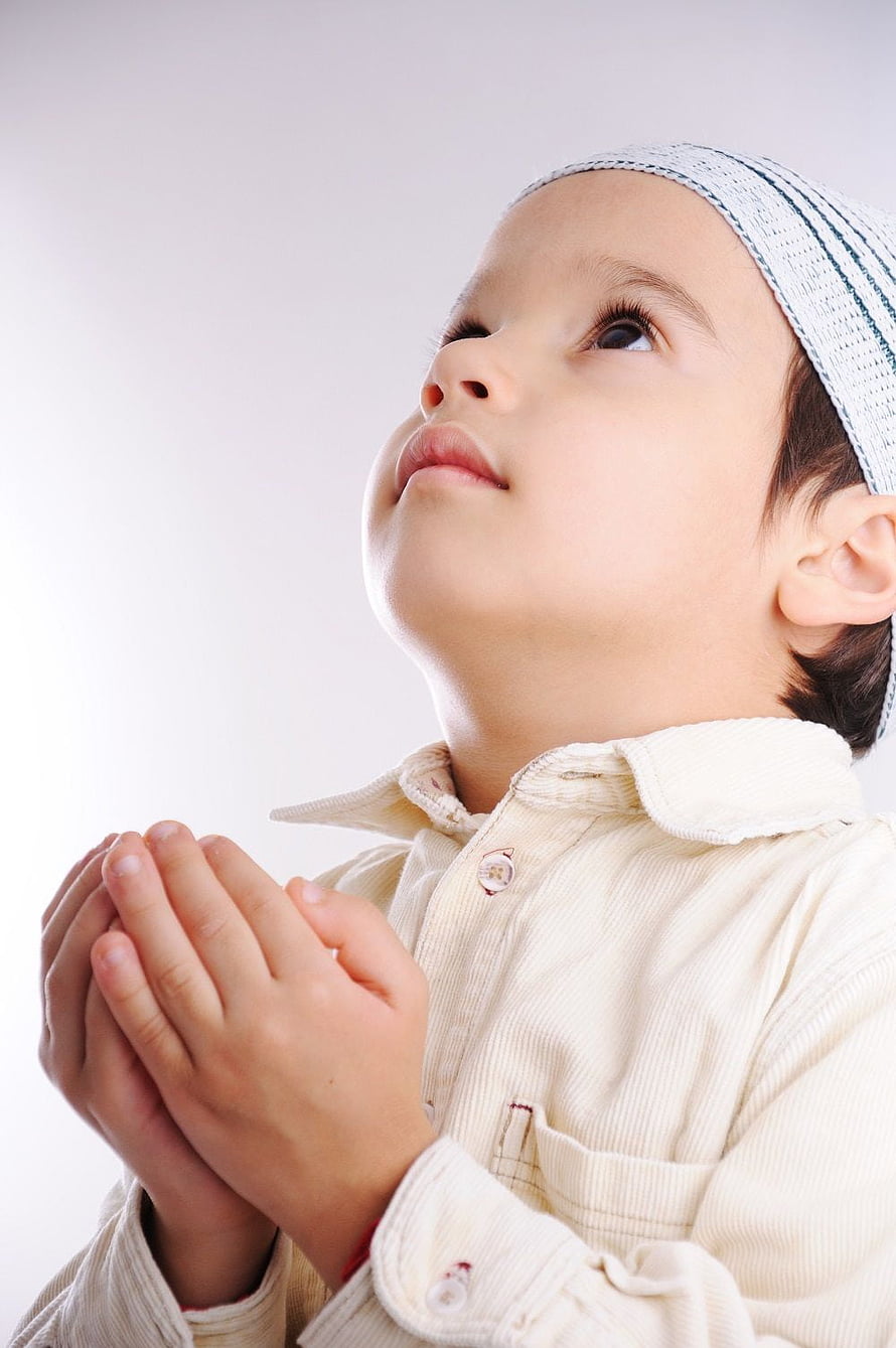 Young Muslim boy in prayer cap with hands clasped in supplication HD phone wallpaper