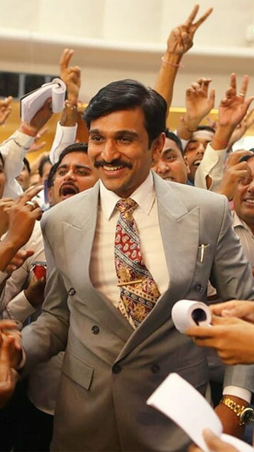 Pratik Gandhi as Harshad Mehta in a Grey Suit Amidst a Celebratory Crowd HD phone wallpaper