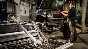 Auto Mechanic Working on Classic Land Rover in Workshop with Tools HD wallpaper