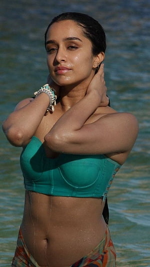 Shraddha Kapoor in a teal bikini top standing in the ocean with wet hair and turquoise jewelry HD phone wallpaper