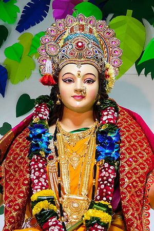 Durga Maa ornate idol adorned with gold jewelry and vibrant floral garlands HD phone wallpaper
