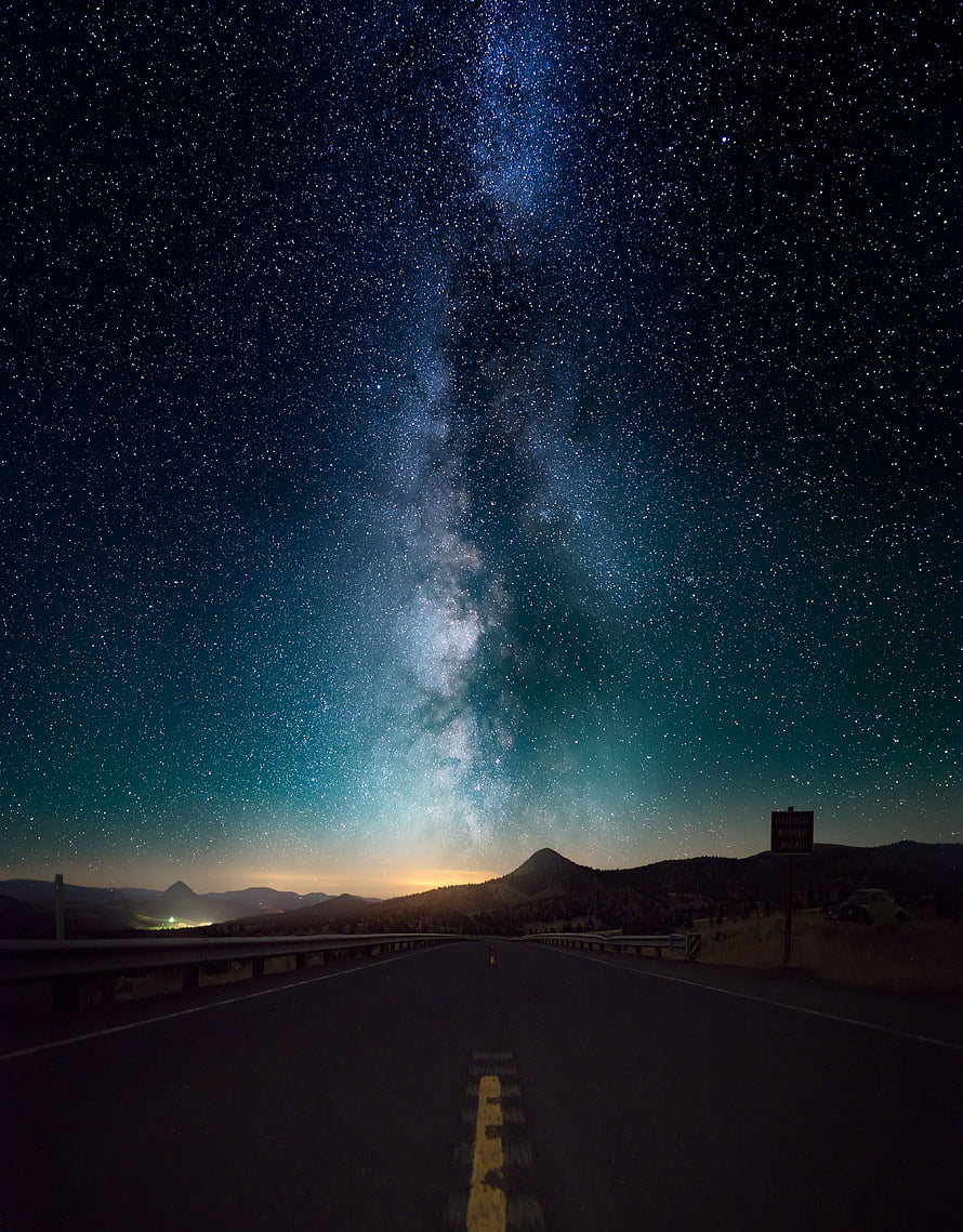 Milky Way Galaxy Arching Over a Desert Highway at Night with Distant Mountain Silhouettes HD phone wallpaper