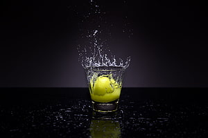 Lemon Dropping Into Water Glass With Dynamic Splash on Black Background HD wallpaper