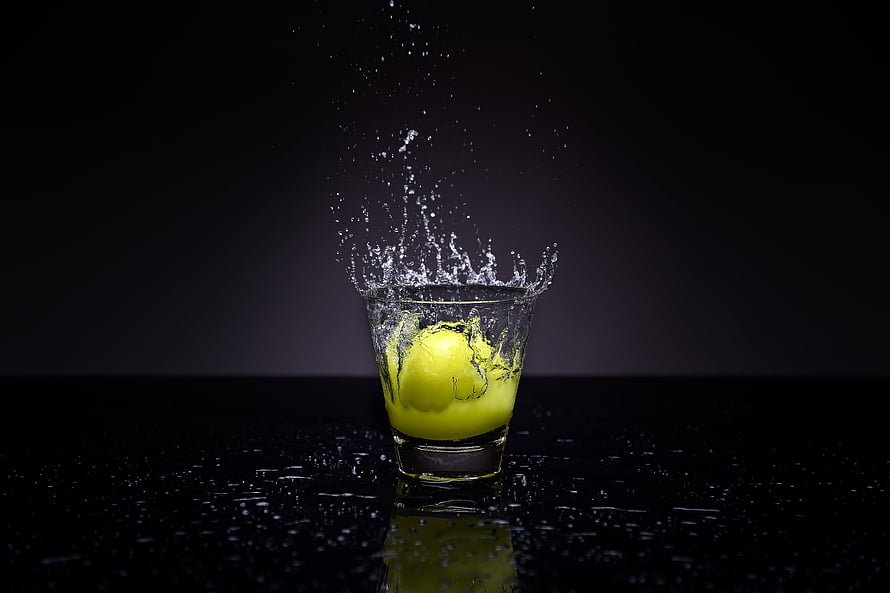 Lemon Dropping Into Water Glass With Dynamic Splash on Black Background HD wallpaper