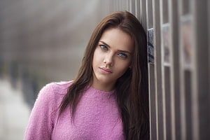 Young woman with long brown hair and blue eyes wearing a pink sweater in a close-up portrait HD wallpaper