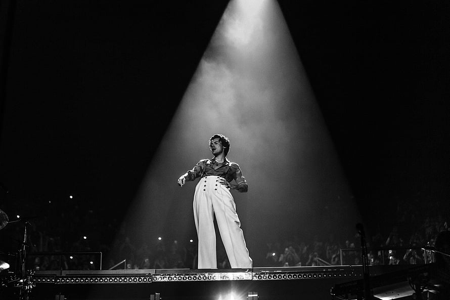 Harry Styles performing on stage under a dramatic spotlight in black and white HD wallpaper