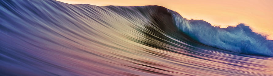 Dramatic Ocean Wave Curling at Sunset with Warm Golden Sky and Blue Foam HD wallpaper