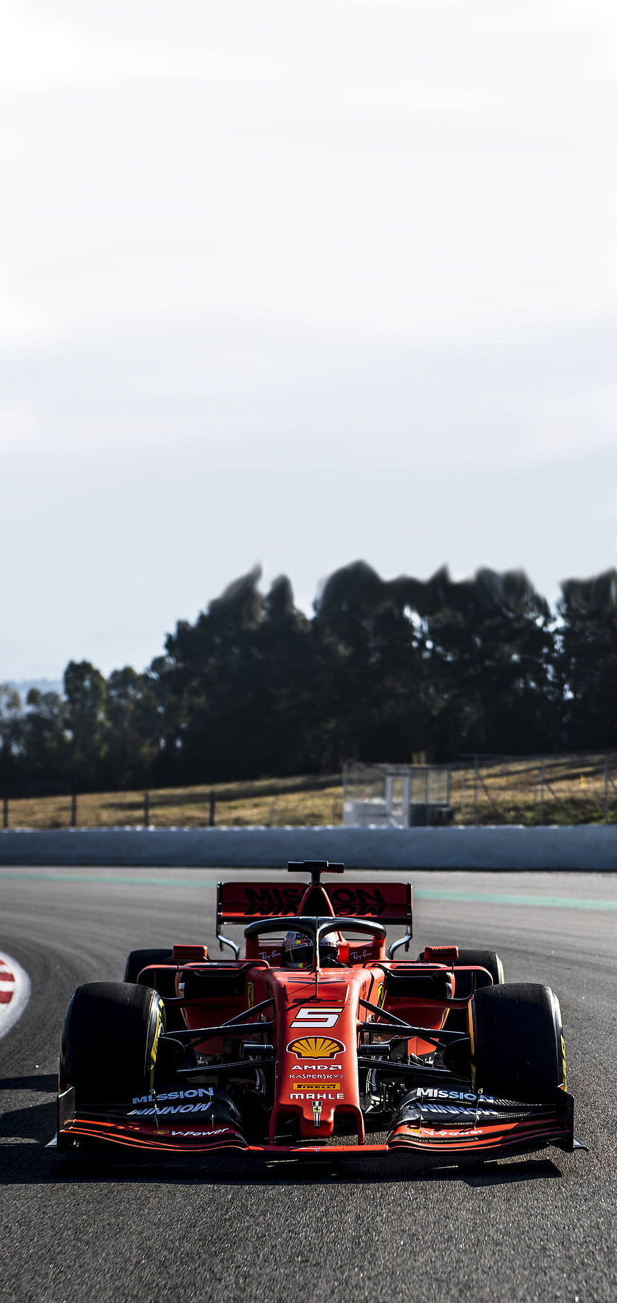 Red Ferrari Formula 1 race car speeding on a track with sponsor logos and open sky background HD phone wallpaper