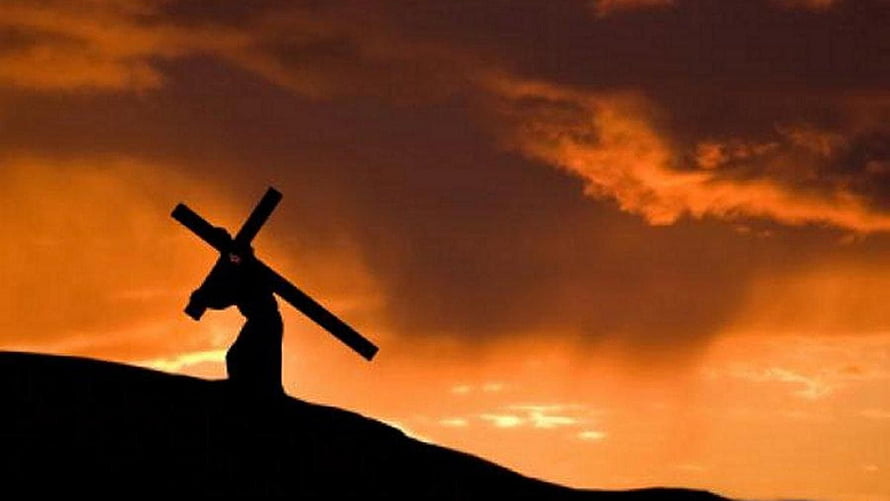Silhouette of Jesus Carrying the Cross Against a Dramatic Orange Sunset Sky HD wallpaper