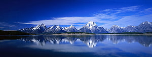 Snow-Capped Mountain Range Reflected in a Calm Alpine Lake Under a Deep Blue Sky HD wallpaper