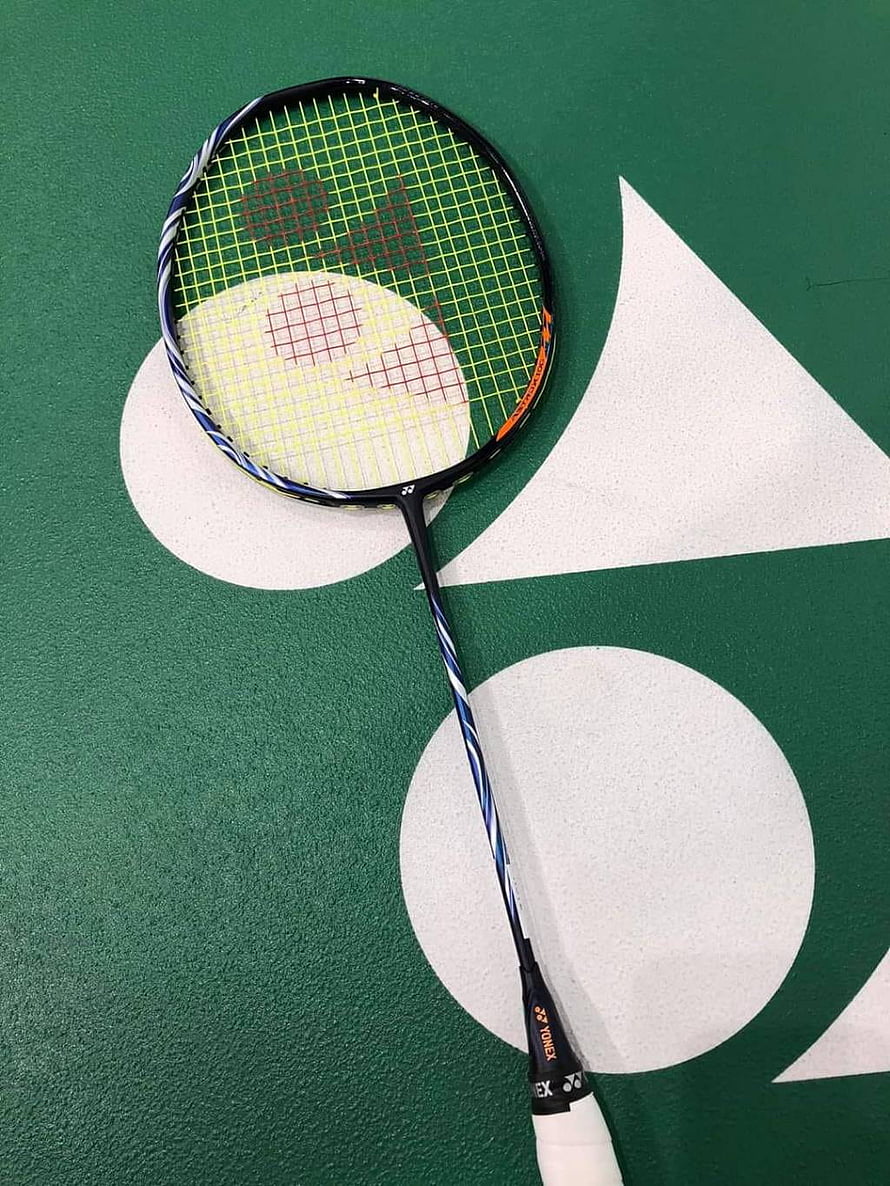 Yonex Astrox 100 badminton racket resting on a green court surface with white geometric markings HD phone wallpaper