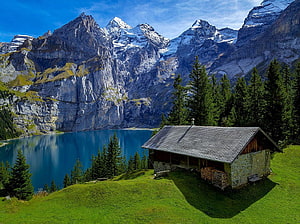 Alpine Mountain Lake with Rustic Cabin and Snow-Capped Peaks in the Swiss Alps HD wallpaper