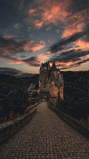 Hogwarts Castle at Dusk with Cobblestone Bridge and Dramatic Sunset Sky HD phone wallpaper