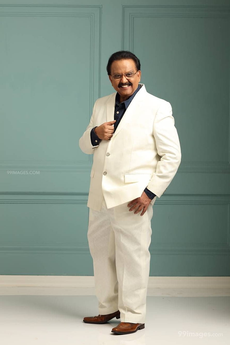 S. P. Balasubrahmanyam in a white suit with brown shoes against a teal wall HD phone wallpaper