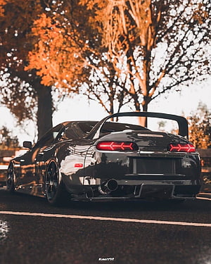 Rear View of a Black Toyota Supra with Large Rear Wing on a Tree-Lined Road HD phone wallpaper