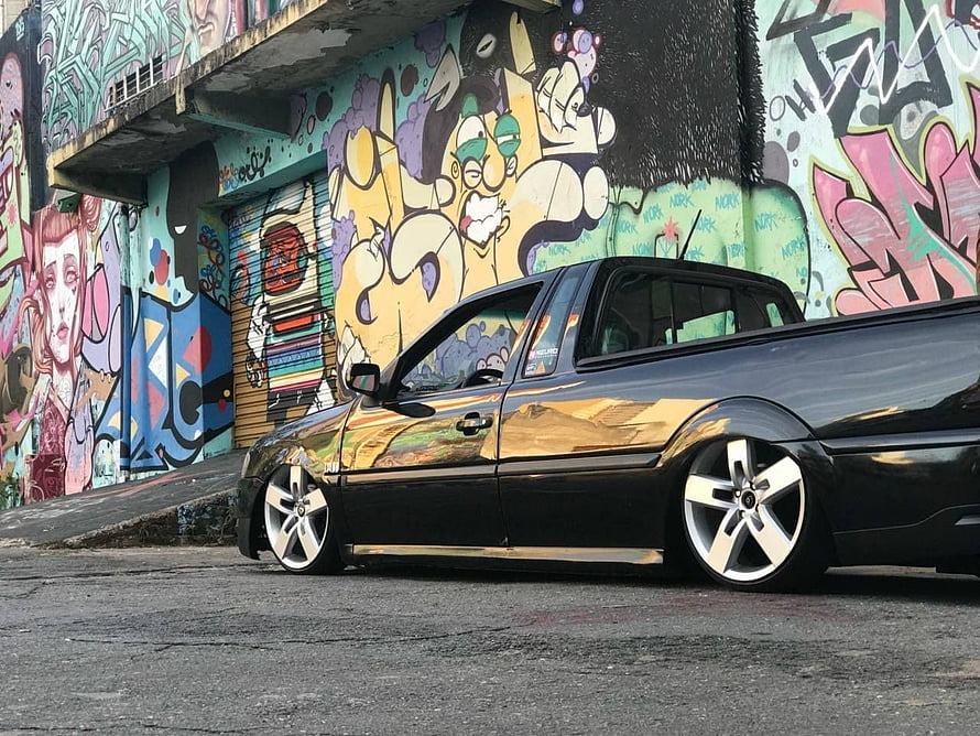 Black VW Saveiro Pickup with Stance Setup Parked Against Vibrant Graffiti Wall HD wallpaper