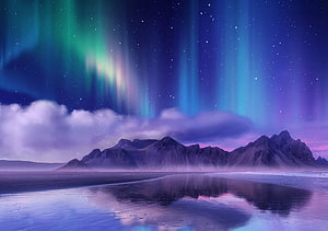 Vibrant Aurora Borealis Dancing Over Rugged Mountains and Reflective Coastal Waters HD wallpaper