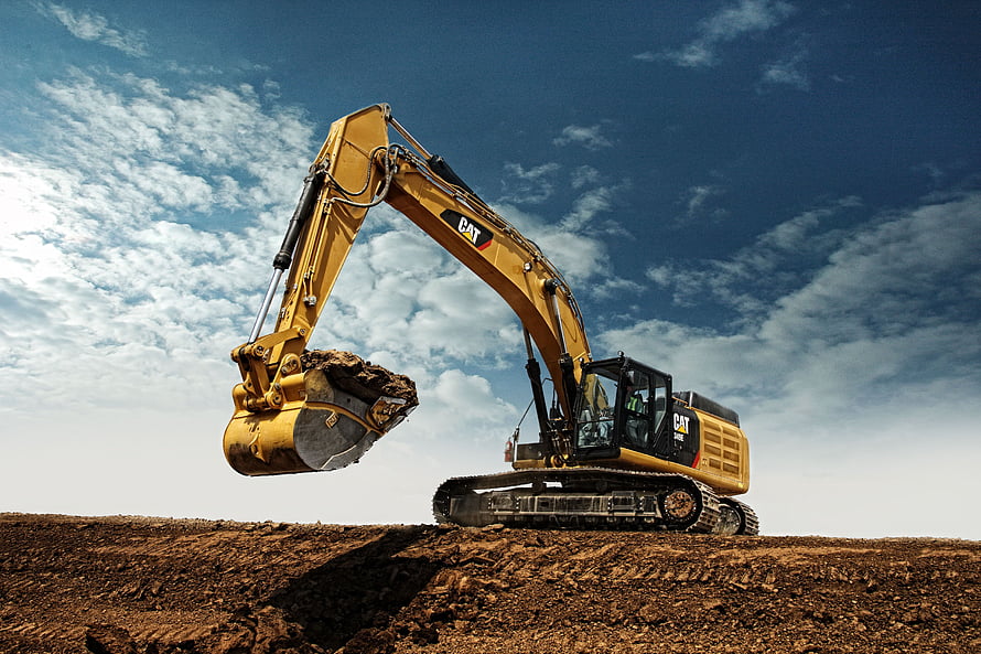 Caterpillar Excavator Lifting Soil on a Construction Site Under a Blue Sky HD wallpaper