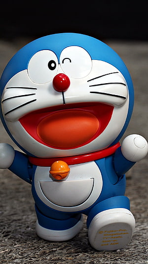 Doraemon Laughing Toy Figure with Red Collar and Orange Bell on Textured Surface HD phone wallpaper