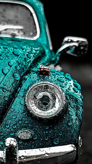 Close-up of a teal Volkswagen Beetle with water droplets on the hood and headlight HD phone wallpaper