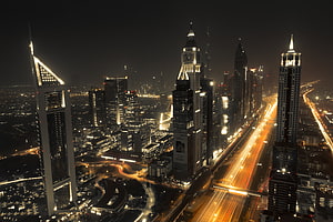 Dubai Downtown skyline at night with illuminated skyscrapers and long-exposure traffic trails HD wallpaper
