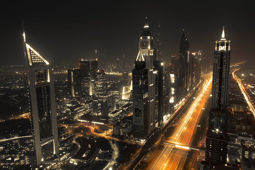 Dubai Downtown skyline at night with illuminated skyscrapers and long-exposure traffic trails HD wallpaper