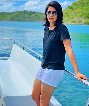 Priya Punia on a boat in a black t-shirt and white shorts with sunglasses HD phone wallpaper