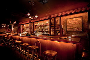 Moody Brick-Walled Speakeasy Bar With Leather Stools And Warm Ambient Lighting HD wallpaper