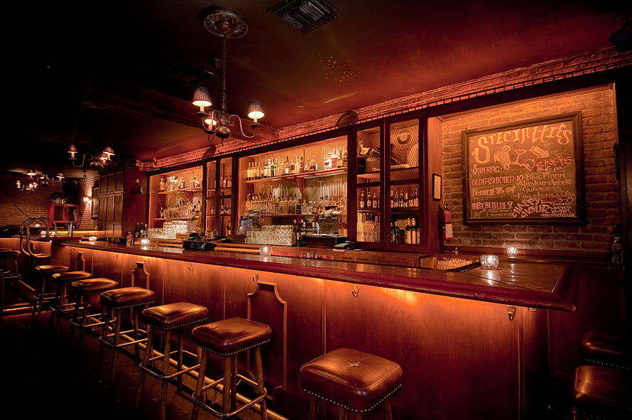 Moody Brick-Walled Speakeasy Bar With Leather Stools And Warm Ambient Lighting HD wallpaper