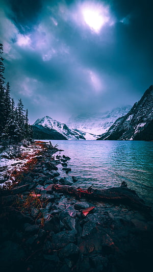 Misty Mountain Lake with Snow-Capped Peaks and Rocky Shoreline HD phone wallpaper