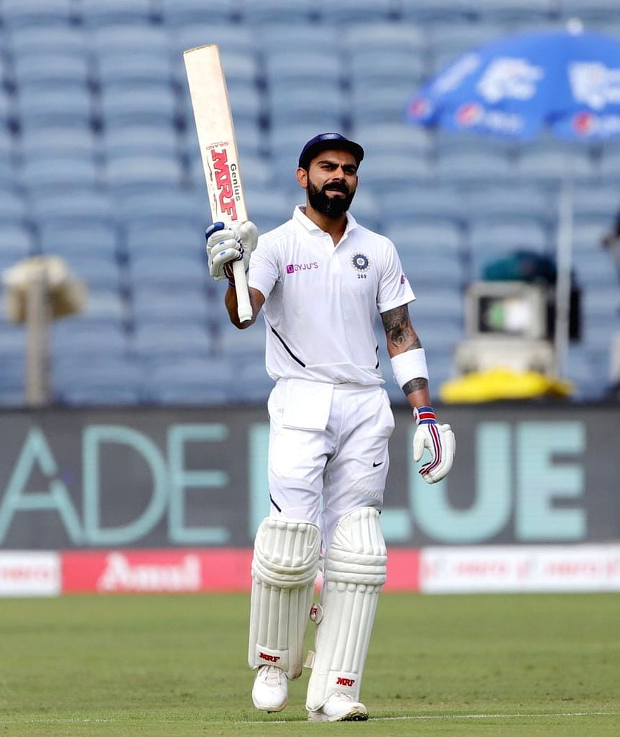 Virat Kohli in Indian Test whites raising bat on the cricket field HD phone wallpaper