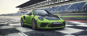 Porsche 911 GT3 RS in lime green parked on a checkered racing track grid HD wallpaper