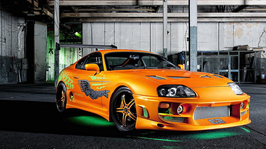 Orange Toyota Supra MK4 with Custom Graphics and Widebody Kit in Industrial Setting HD wallpaper