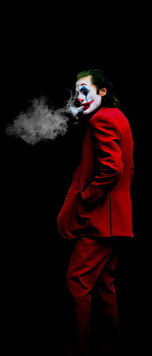 Joker in red suit smoking cigarette against black background HD phone wallpaper