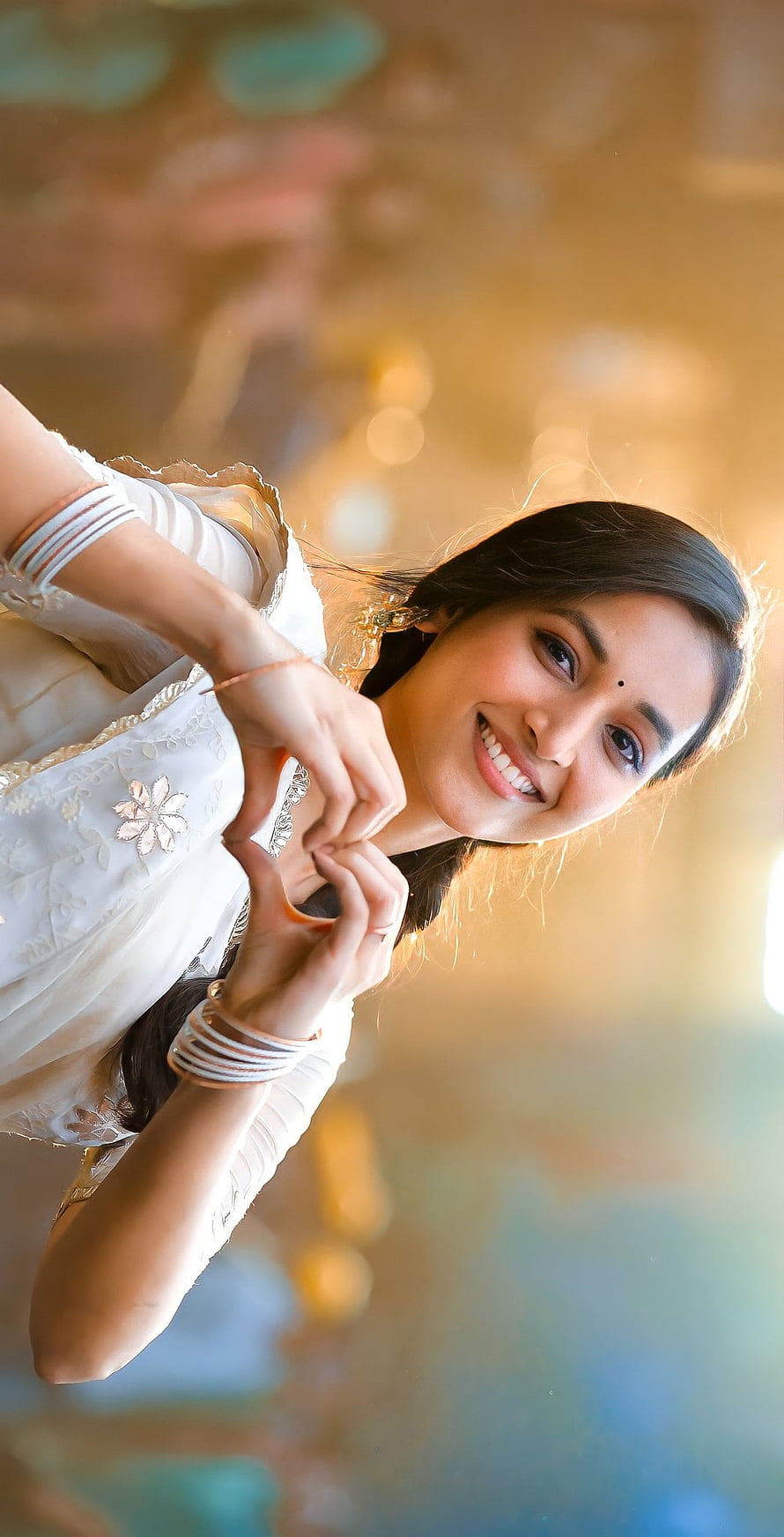 Srinidhi Shetty in White Embroidered Outfit Making Heart Gesture in Warm Sunlight HD phone wallpaper