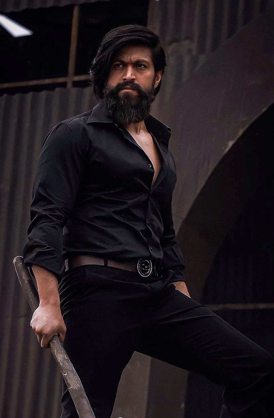 Yash in KGF 2 as Rocky Bhai in a black shirt holding a machete in an industrial setting HD phone wallpaper