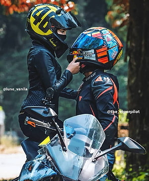 Biker Couple in Full Gear Adjusting Helmets on a Motorcycle in a Forest Setting HD phone wallpaper